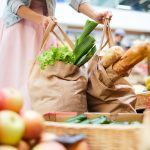 Woman picking heavy shopping bags in food store